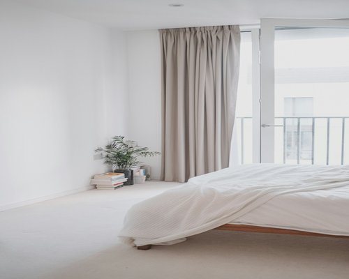A comfortable clean bedroom with neutral tones and curtains gently moving, representing optimal conditions for sleep